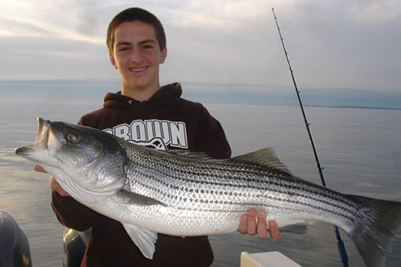 Young Man Holding Huge Striped Bas He Caught